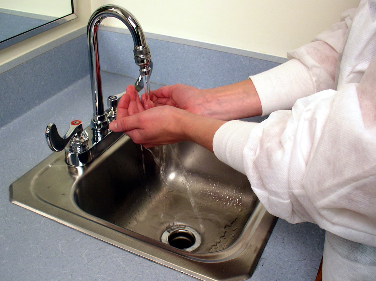 A person washing their hands with soap and clean water